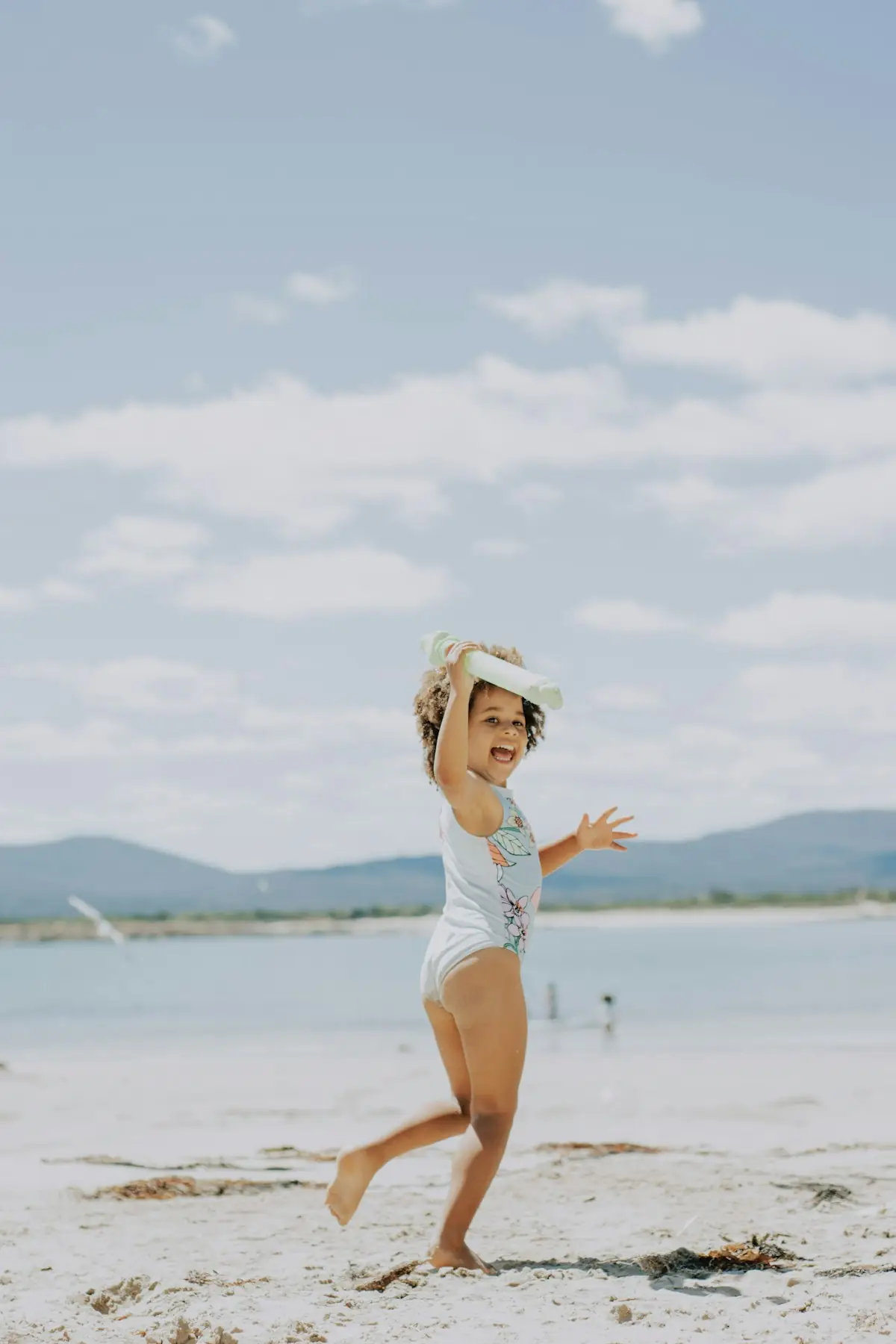 A child running joyfully across wet sand at the beach