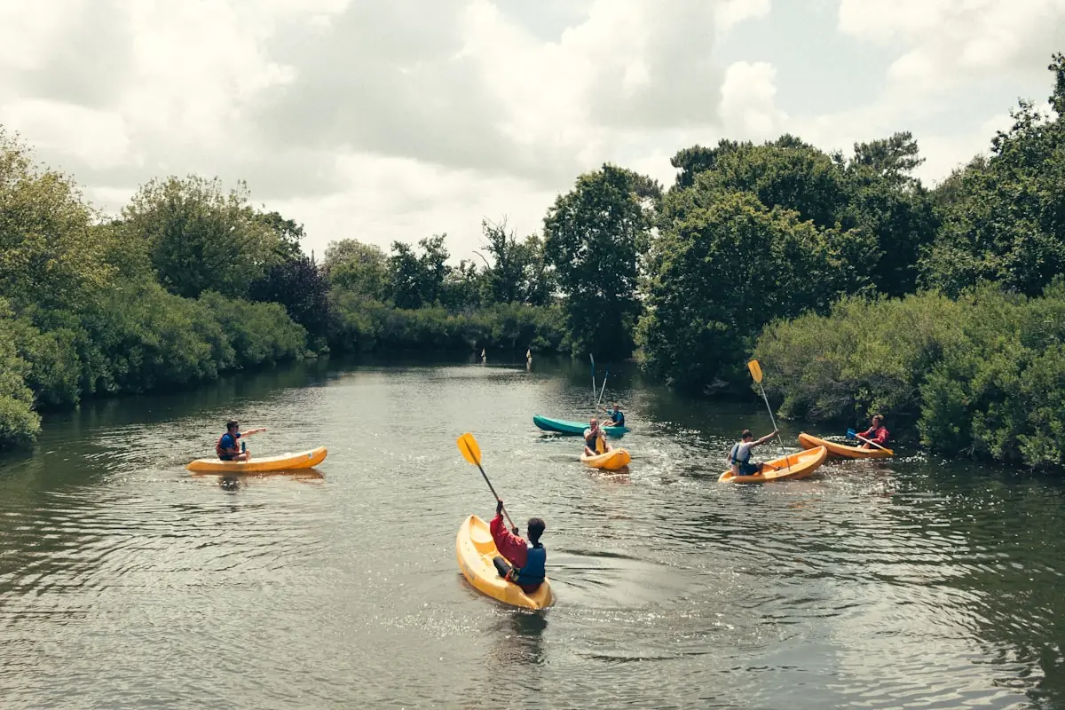 Students paddling kayaks together on calm water
